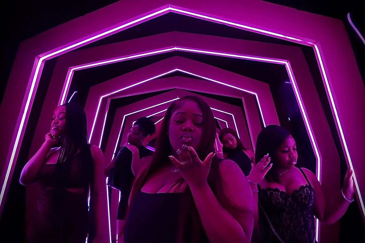 Group under pink neon light tunnel at a night event